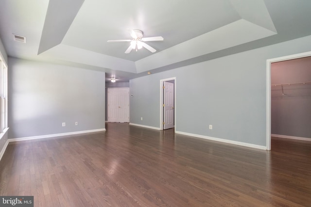 spare room featuring a raised ceiling, ceiling fan, and dark wood-type flooring