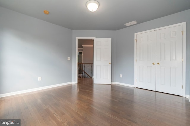 unfurnished bedroom with dark hardwood / wood-style flooring and a closet