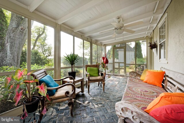 sunroom with ceiling fan and beam ceiling