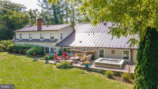 back of house with a hot tub, a lawn, and a patio