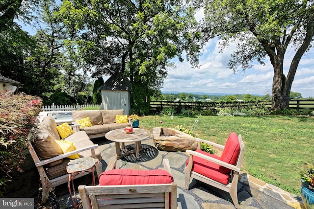 view of patio with an outdoor living space with a fire pit and a storage shed