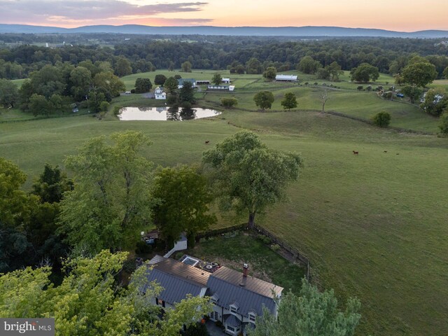 aerial view at dusk featuring a water view and a rural view