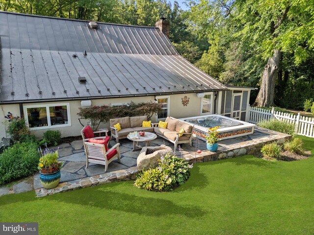 back of property with a hot tub, outdoor lounge area, a lawn, and a patio area