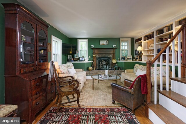 living room featuring a brick fireplace and wood-type flooring