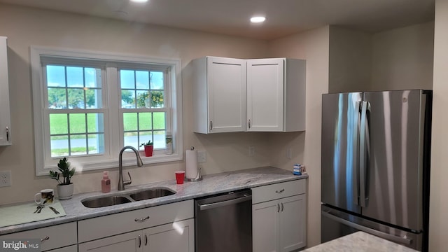 kitchen with light stone counters, sink, white cabinets, and stainless steel appliances