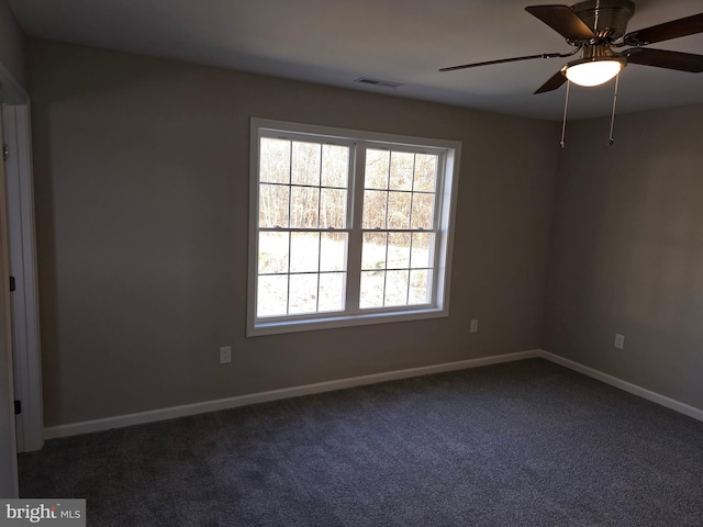 spare room with ceiling fan and dark colored carpet