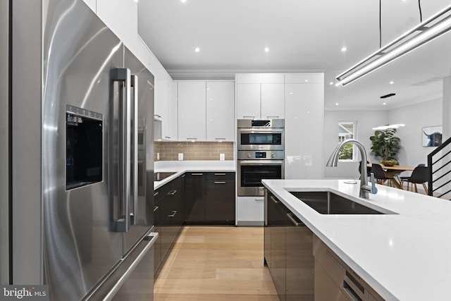 kitchen featuring light hardwood / wood-style flooring, stainless steel appliances, crown molding, sink, and white cabinetry