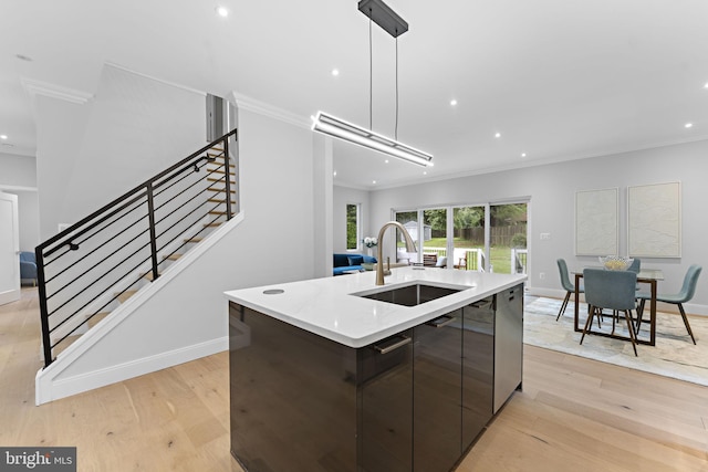 kitchen with sink, a kitchen island with sink, light hardwood / wood-style flooring, and decorative light fixtures