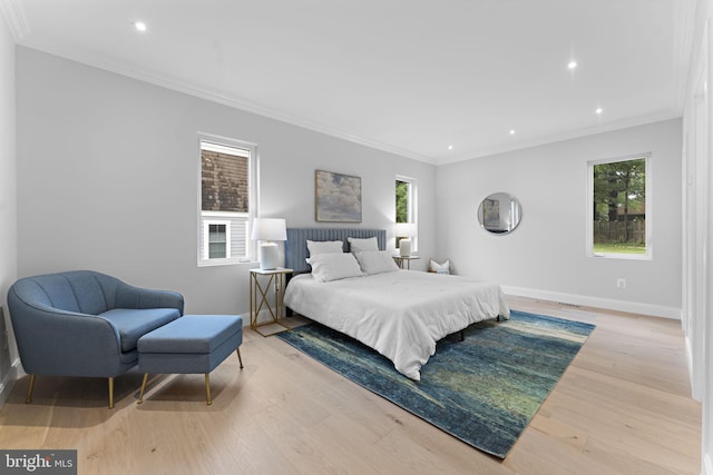 bedroom featuring light hardwood / wood-style floors, multiple windows, and crown molding