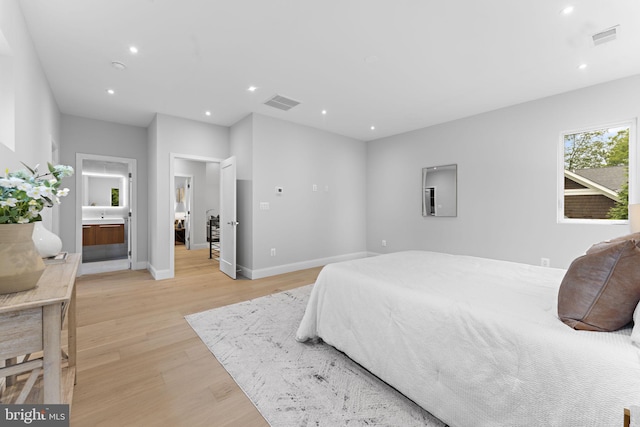 bedroom with ensuite bathroom and light wood-type flooring