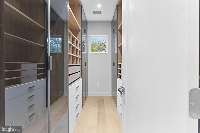 walk in closet with light hardwood / wood-style floors