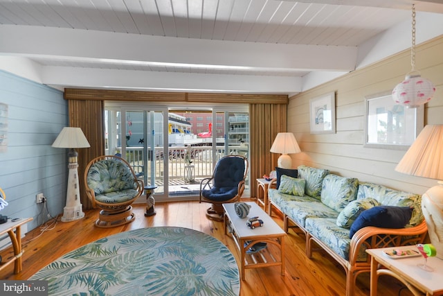 living room featuring hardwood / wood-style floors, beam ceiling, and wooden walls