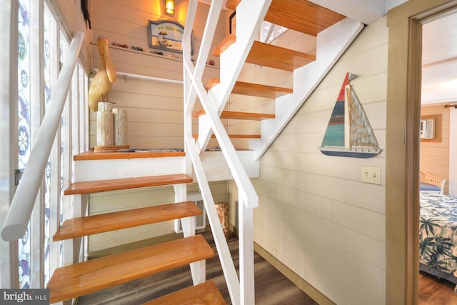 staircase featuring hardwood / wood-style floors and wooden walls