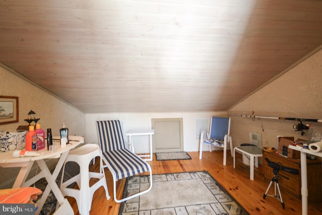 interior space featuring lofted ceiling, wood ceiling, wood finished floors, and a textured wall