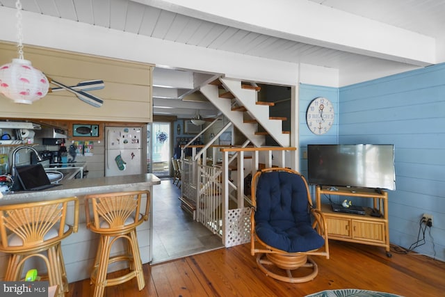 living room with stairway, dark wood-style flooring, and wooden walls