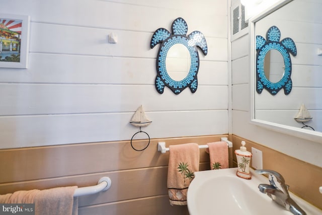 bathroom featuring sink and wood walls