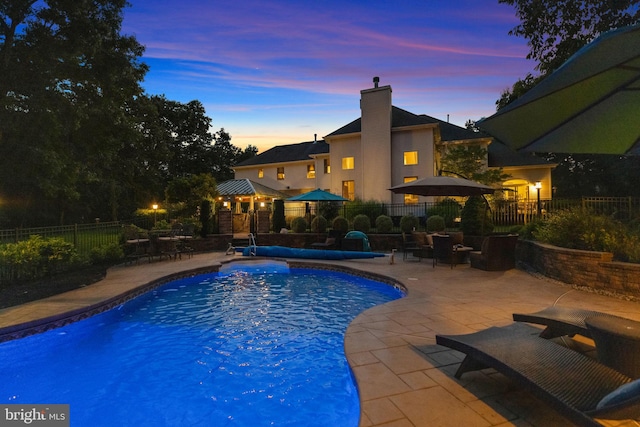 pool at dusk featuring a patio