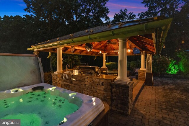 patio terrace at dusk featuring a gazebo and a hot tub