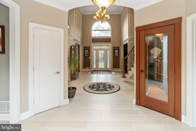 tiled entryway featuring crown molding and a chandelier