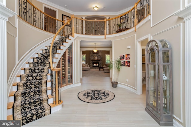 tiled entrance foyer with a towering ceiling, crown molding, and a large fireplace