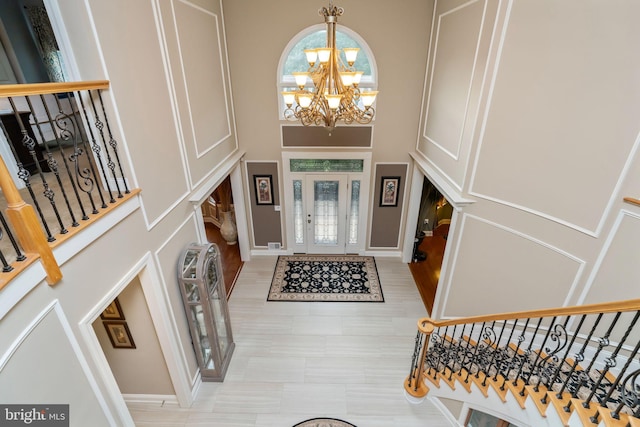 entrance foyer featuring light tile patterned flooring, a high ceiling, and a chandelier