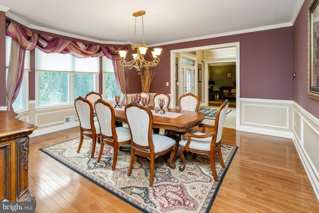 dining space with crown molding, a chandelier, and wood-type flooring