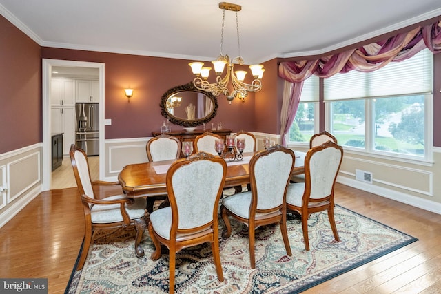 dining room with light wood-type flooring, a notable chandelier, and ornamental molding