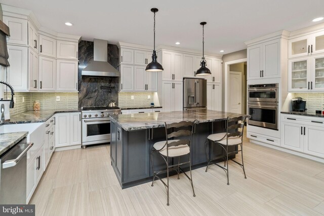 kitchen featuring appliances with stainless steel finishes, decorative backsplash, and wall chimney range hood