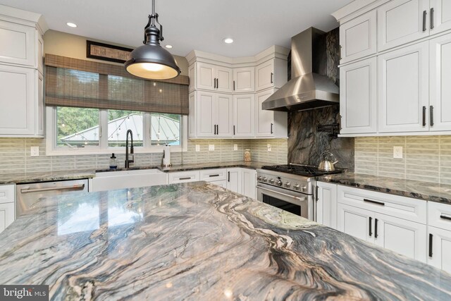 kitchen with wall chimney range hood, tasteful backsplash, white cabinets, stone countertops, and stainless steel appliances