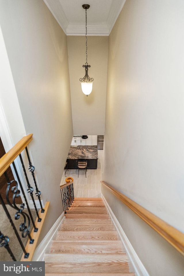 staircase with crown molding and wood-type flooring