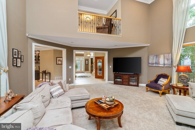 living room with a towering ceiling, crown molding, light colored carpet, and a healthy amount of sunlight