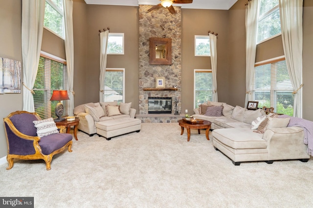 carpeted living room featuring ceiling fan, a fireplace, and a high ceiling