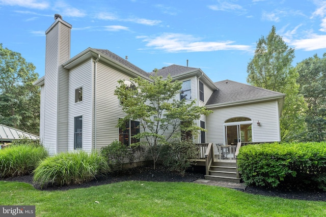 rear view of property featuring a wooden deck and a lawn