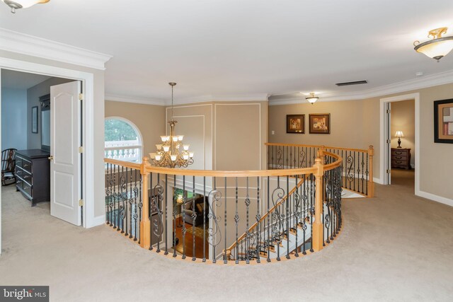 hall with ornamental molding, light carpet, and a chandelier