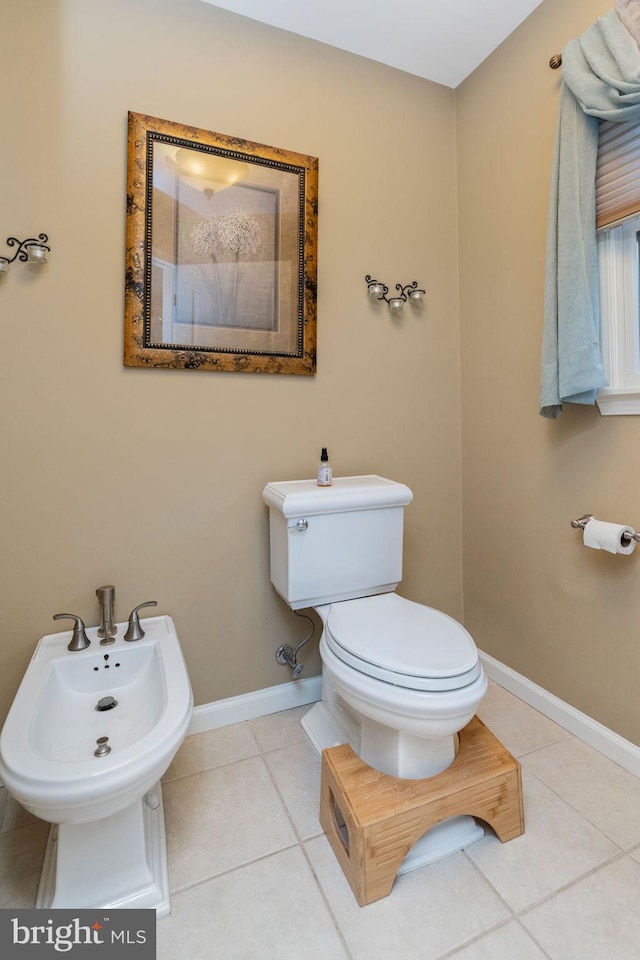 bathroom with tile patterned floors, a bidet, and toilet