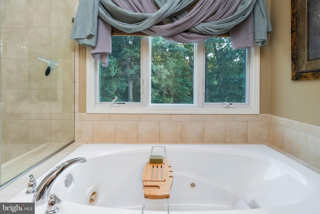 bathroom with a relaxing tiled tub and a healthy amount of sunlight