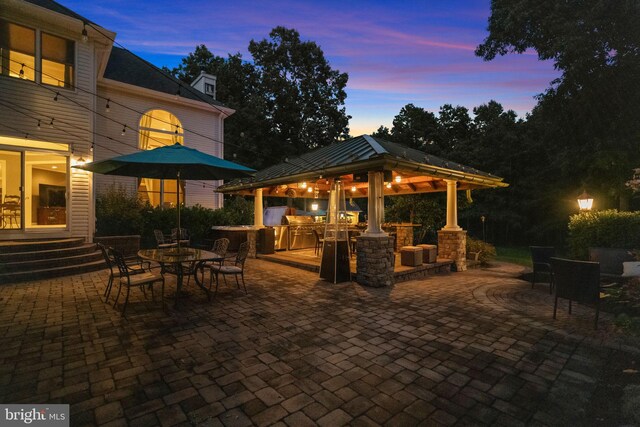 patio terrace at dusk featuring a gazebo and an outdoor bar