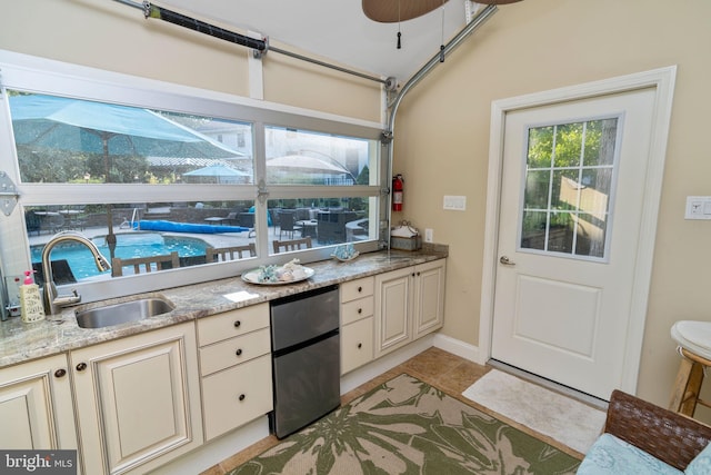 kitchen featuring sink, light stone counters, light tile patterned flooring, and cream cabinetry