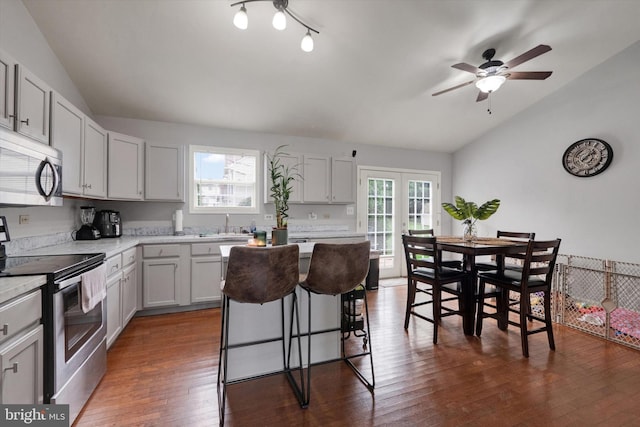 kitchen featuring white cabinets, lofted ceiling, stainless steel appliances, dark hardwood / wood-style floors, and a breakfast bar