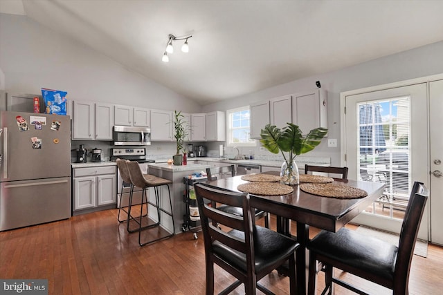 dining area featuring vaulted ceiling, dark hardwood / wood-style floors, and sink