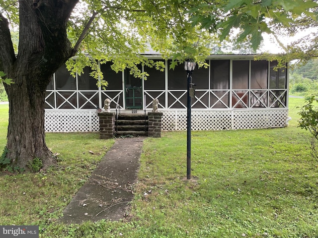 back of property with a yard and a sunroom