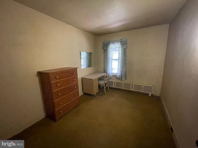 unfurnished bedroom featuring dark colored carpet and a baseboard radiator