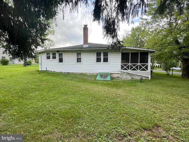 rear view of house featuring a sunroom and a lawn