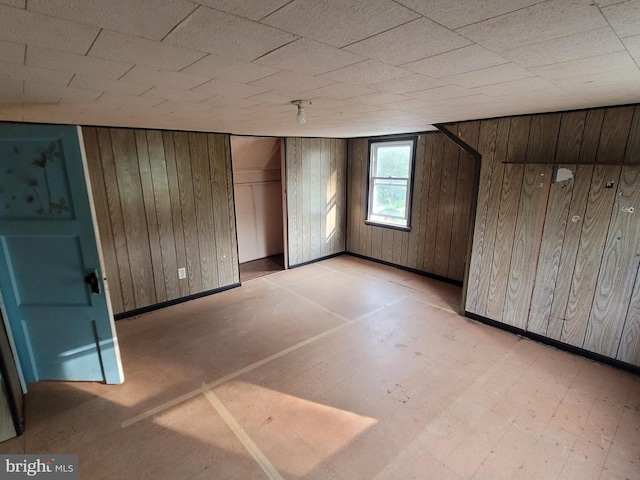 bonus room featuring wood walls