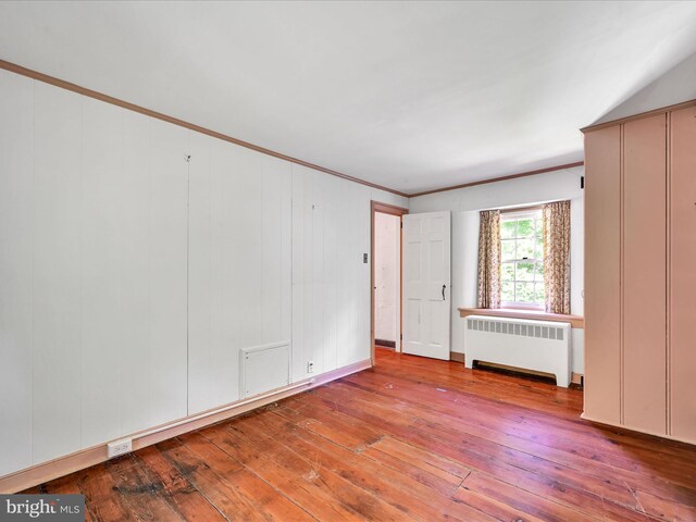 unfurnished room featuring crown molding, radiator heating unit, and hardwood / wood-style floors