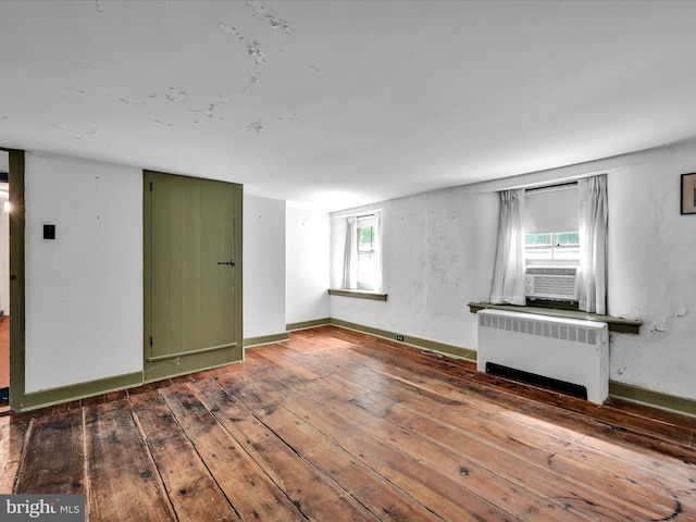 spare room featuring radiator, a healthy amount of sunlight, and wood-type flooring