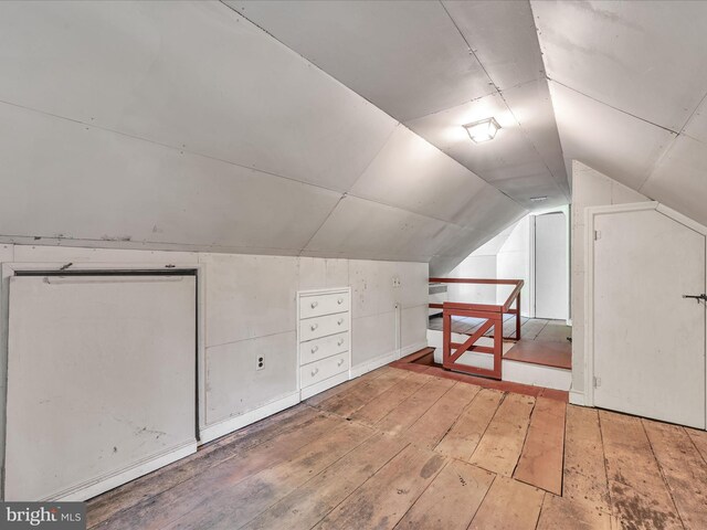 additional living space with light hardwood / wood-style floors and lofted ceiling