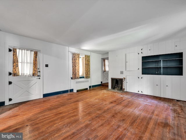 unfurnished living room with vaulted ceiling, wood-type flooring, and radiator heating unit