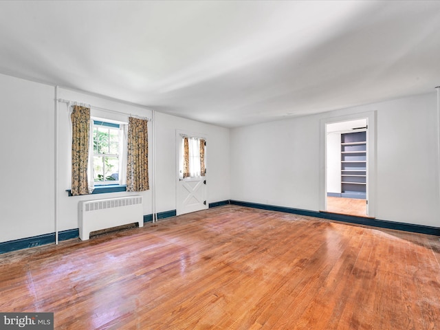 unfurnished room featuring radiator heating unit and hardwood / wood-style flooring