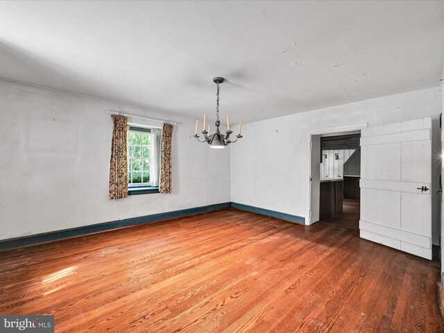 empty room with a notable chandelier and hardwood / wood-style floors